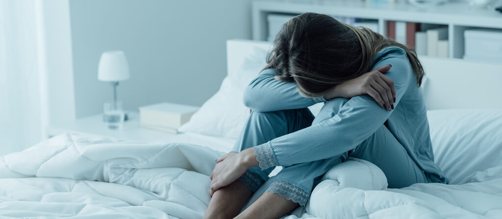 upset woman sitting on bed