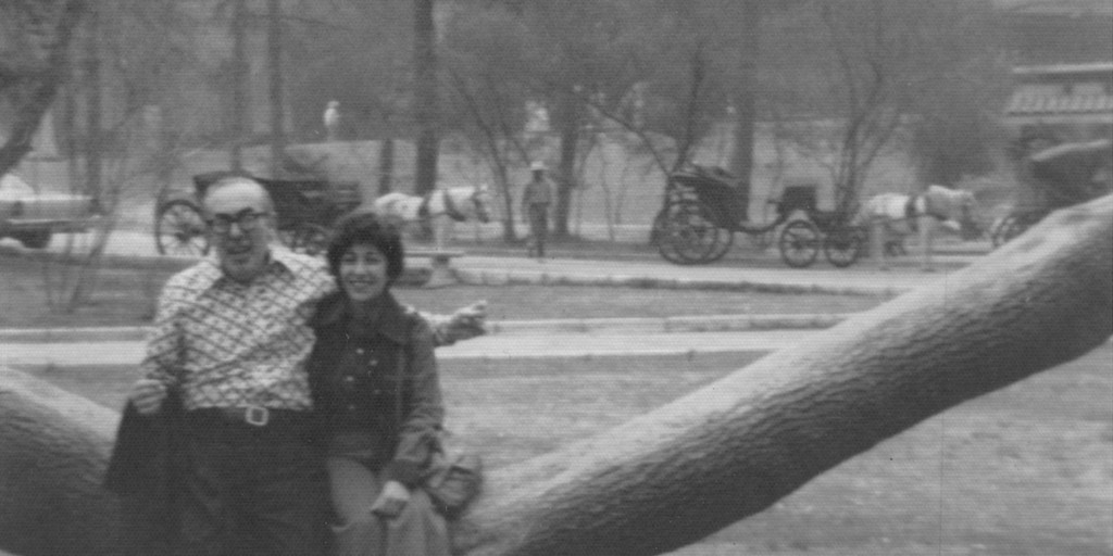 black and white photo of parents sitting on tree